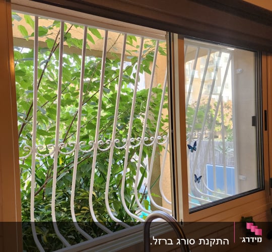 חלון עם סורגים לבנים ופרפרים דקורטיביים